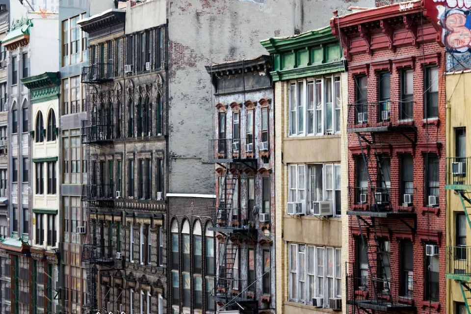 Colorful brick apartment buildings with fire escapes in Chinatown, New York City.